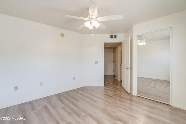 unfurnished bedroom with ceiling fan, visible vents, light wood-type flooring, baseboards, and a closet