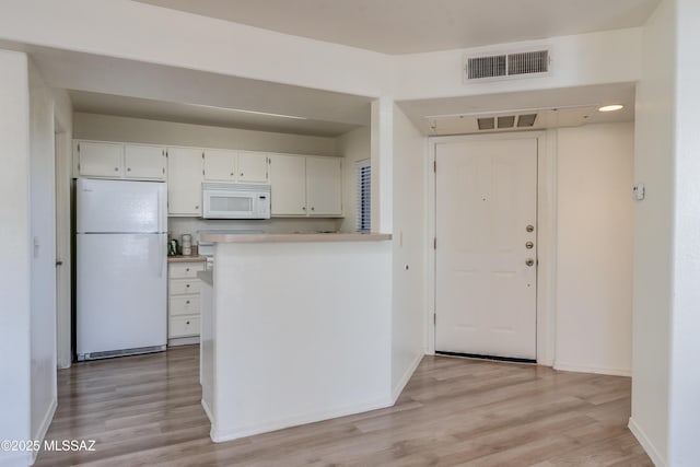 kitchen with light wood-type flooring, white appliances, white cabinetry, and visible vents