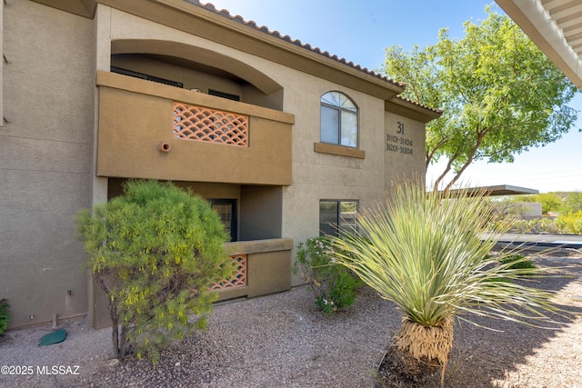 exterior space with stucco siding and a tile roof