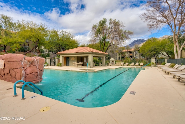 pool with a patio area, fence, and a mountain view