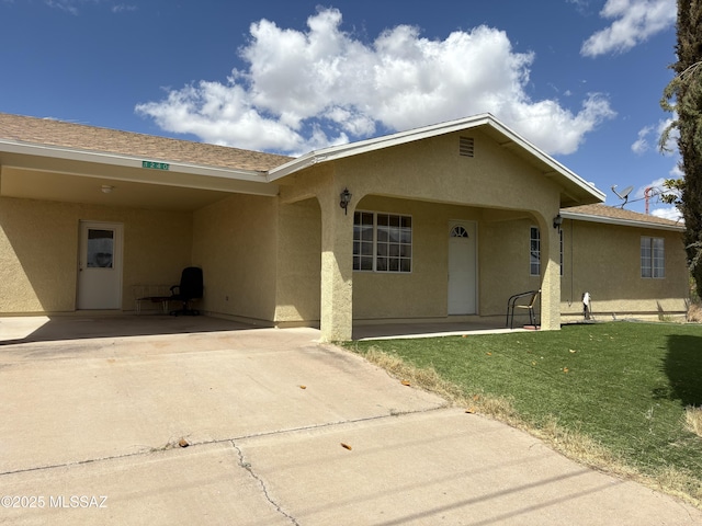view of front facade with stucco siding, a front lawn, and concrete driveway