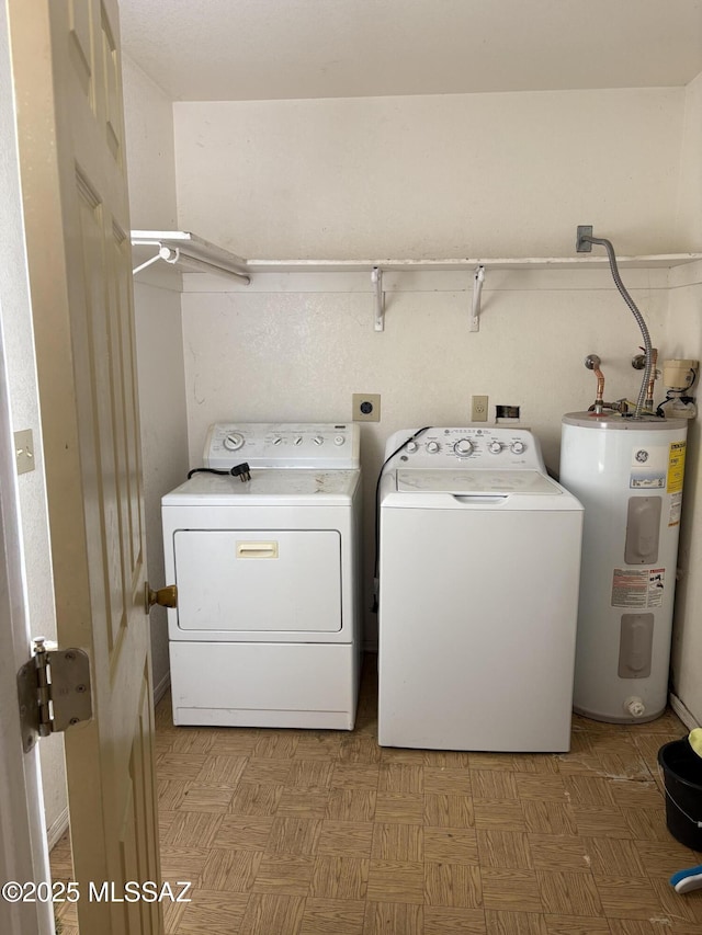 clothes washing area featuring light floors, electric water heater, washer and dryer, and laundry area