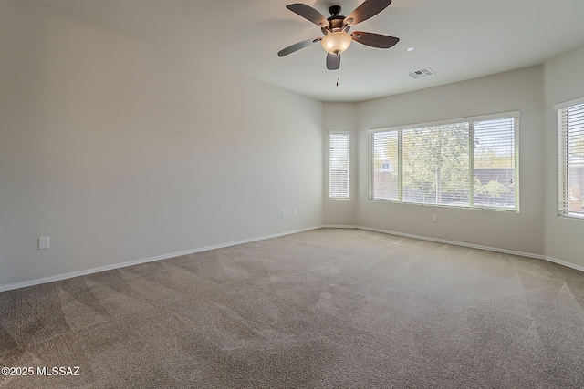 empty room featuring light colored carpet, ceiling fan, visible vents, and baseboards