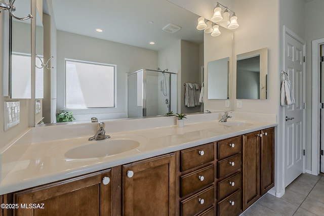 bathroom featuring double vanity, tile patterned floors, a shower stall, and a sink