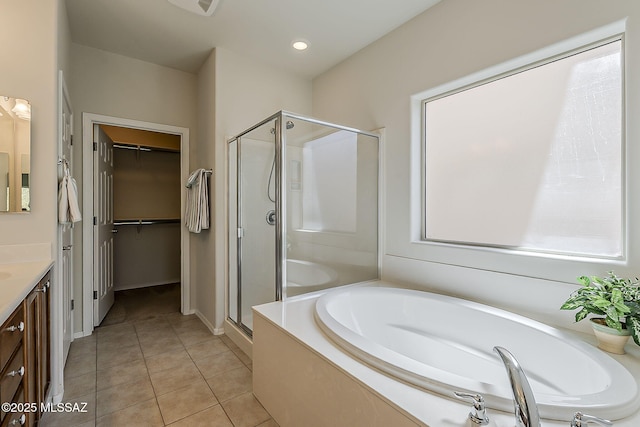 bathroom with vanity, a walk in closet, tile patterned floors, a bath, and a shower stall
