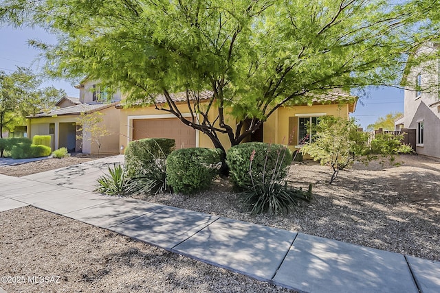 view of front of home featuring stucco siding, a tiled roof, and concrete driveway