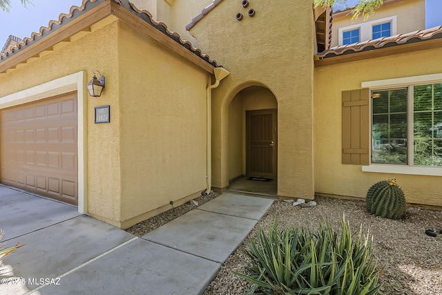 entrance to property featuring a tiled roof and stucco siding