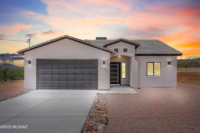 view of front of property featuring concrete driveway, a garage, a tiled roof, and stucco siding