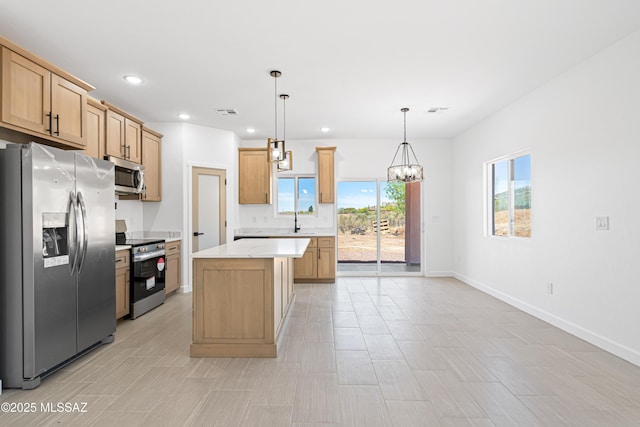 kitchen with a center island, baseboards, a notable chandelier, and appliances with stainless steel finishes
