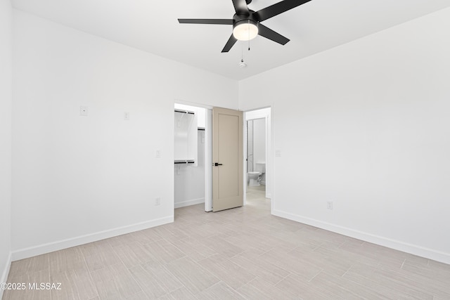 unfurnished bedroom featuring a ceiling fan, baseboards, a closet, and a walk in closet