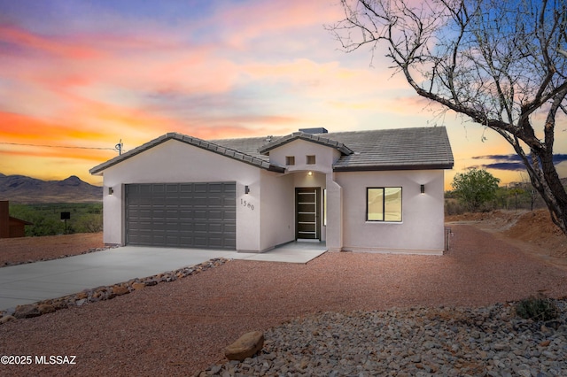 view of front of home with a garage, a tile roof, stucco siding, and concrete driveway