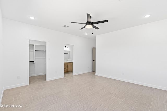 unfurnished bedroom with a walk in closet, baseboards, light wood-style floors, and recessed lighting