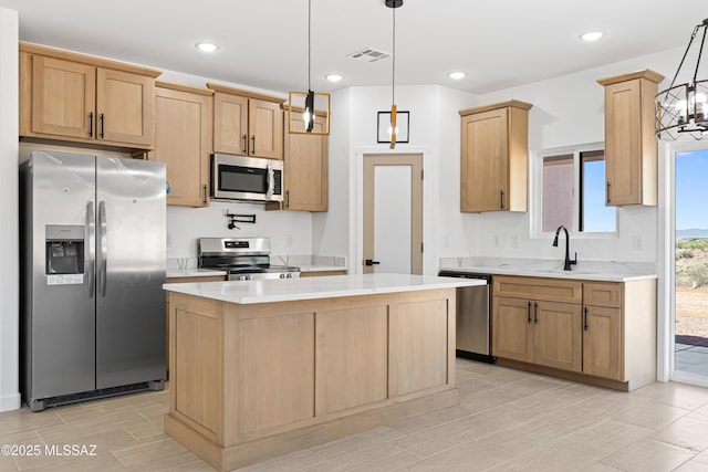 kitchen with stainless steel appliances, a sink, visible vents, pendant lighting, and a kitchen island