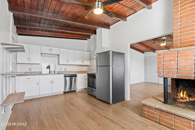 kitchen with appliances with stainless steel finishes, a sink, beam ceiling, a ceiling fan, and wood ceiling