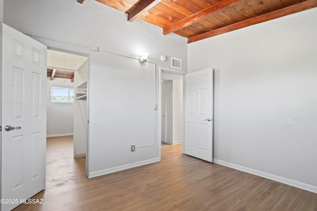 unfurnished bedroom featuring visible vents, beamed ceiling, baseboards, wood ceiling, and light wood-style flooring