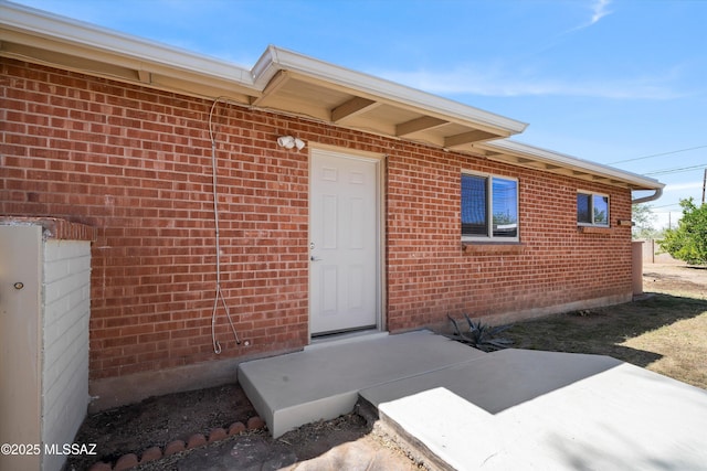 entrance to property with a patio area and brick siding