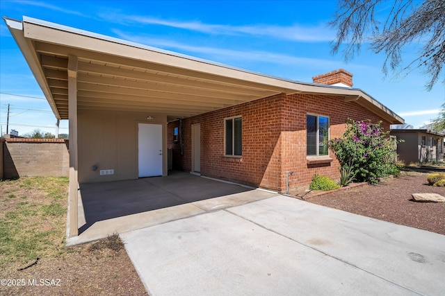 single story home with brick siding, driveway, a chimney, and a carport