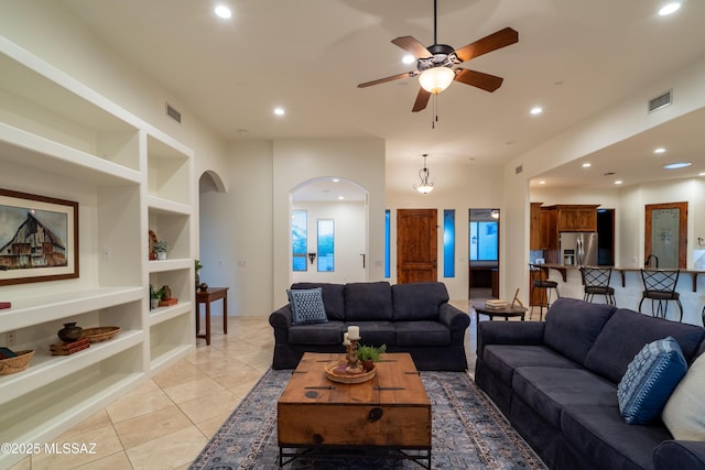 living area with ceiling fan, visible vents, arched walkways, built in shelves, and light tile patterned floors