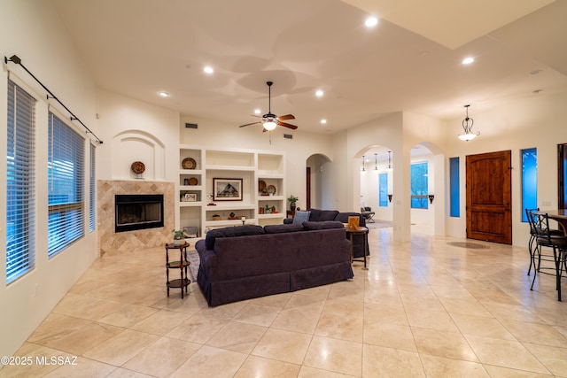 living area featuring recessed lighting, arched walkways, a ceiling fan, and a tile fireplace