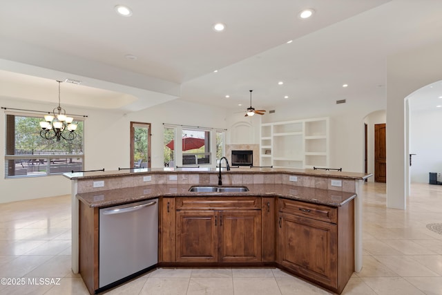 kitchen featuring stainless steel dishwasher, open floor plan, arched walkways, a sink, and ceiling fan with notable chandelier