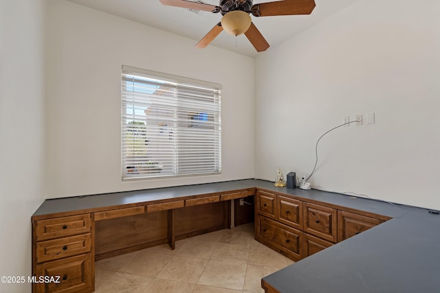 unfurnished office with light tile patterned floors, a ceiling fan, and built in desk