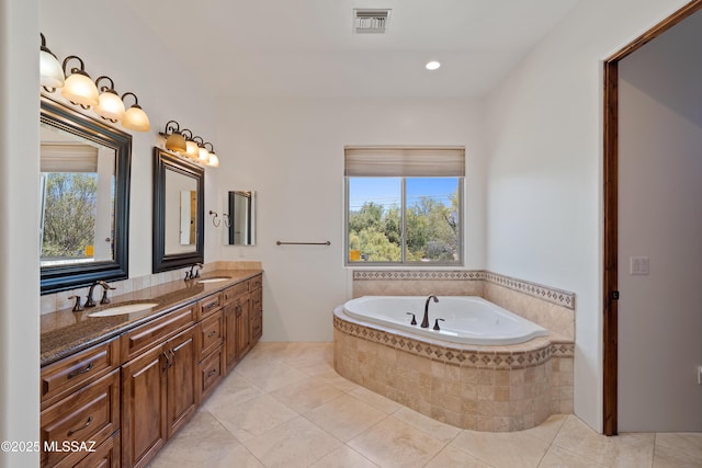 full bath with tile patterned flooring, visible vents, a sink, and a garden tub