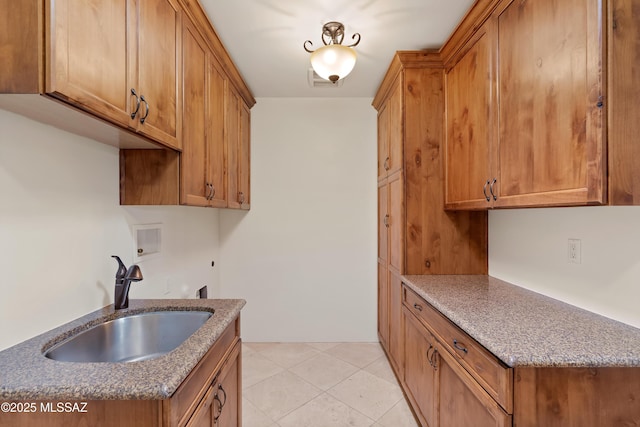 washroom with cabinet space, light tile patterned flooring, washer hookup, and a sink