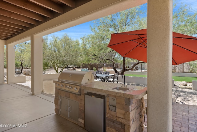 view of patio with area for grilling, fence, and a sink