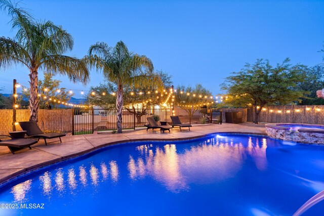view of pool featuring a patio area, fence, and a pool with connected hot tub