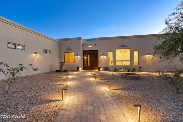 adobe home featuring a patio, an outdoor fire pit, and stucco siding
