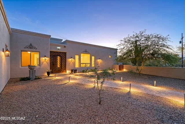 view of front facade featuring a fenced backyard and stucco siding