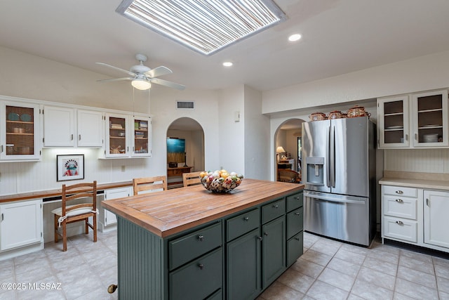 kitchen featuring visible vents, butcher block countertops, stainless steel refrigerator with ice dispenser, white cabinetry, and arched walkways