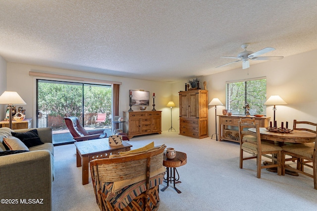living area with a textured ceiling, ceiling fan, and light carpet