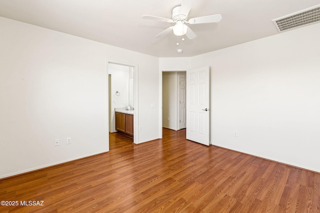 unfurnished bedroom featuring ceiling fan, baseboards, wood finished floors, and visible vents