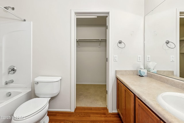 bathroom featuring toilet, wood finished floors, vanity, shower / bath combination, and baseboards