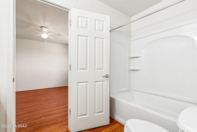 full bath with toilet, baseboards, wood finished floors, ceiling fan, and shower / tub combination