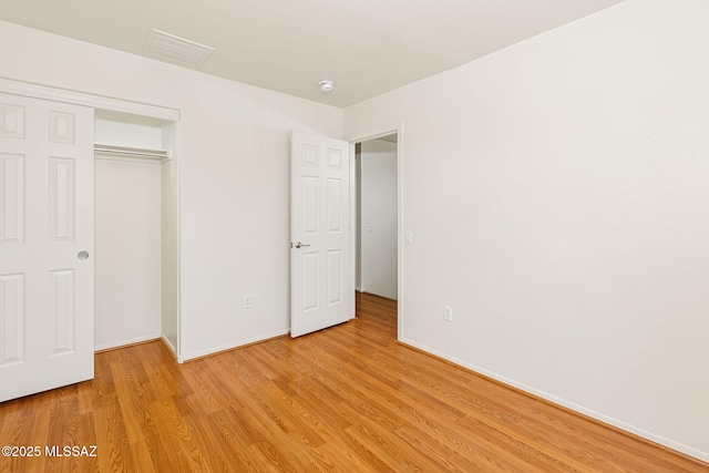 unfurnished bedroom featuring a closet, light wood-style flooring, visible vents, and baseboards