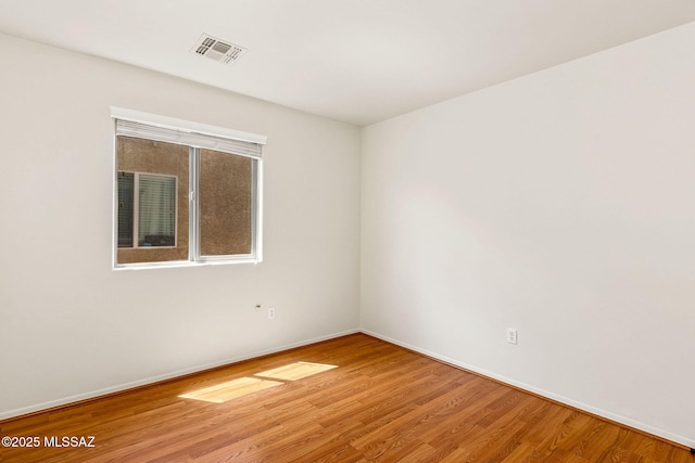 unfurnished room featuring wood finished floors, visible vents, and baseboards