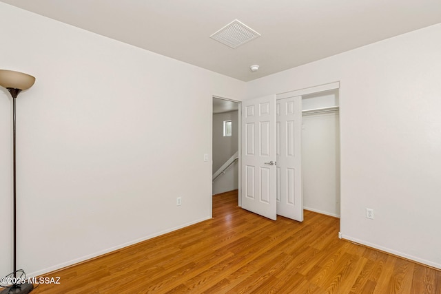 unfurnished bedroom with baseboards, a closet, visible vents, and light wood-style flooring