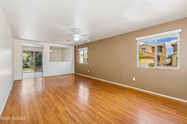 spare room featuring baseboards, light wood finished floors, and plenty of natural light