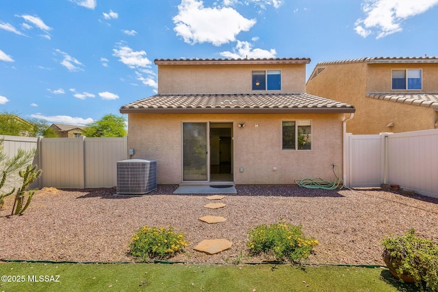 rear view of property featuring a tile roof, a fenced backyard, central air condition unit, and stucco siding