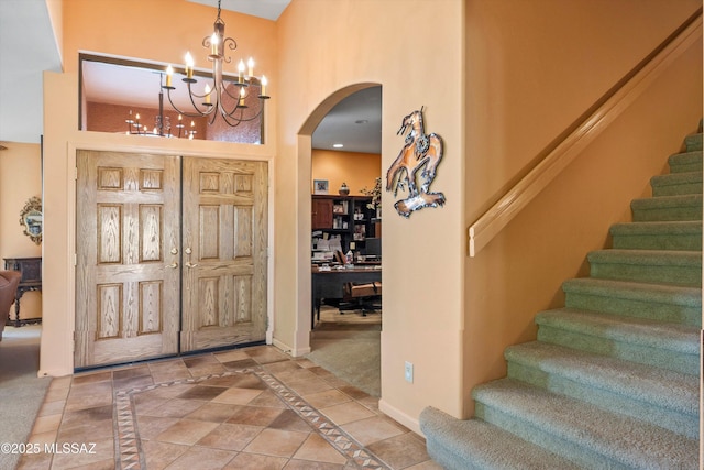 foyer with arched walkways, baseboards, a notable chandelier, a high ceiling, and stairway