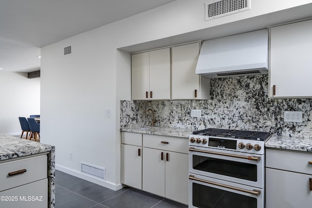 1720 W Cessna Way, Tucson, AZ 85755 - kitchen featuring range with two ovens, decorative backsplash, custom range hood, dark tile patterned flooring, and light stone countertops