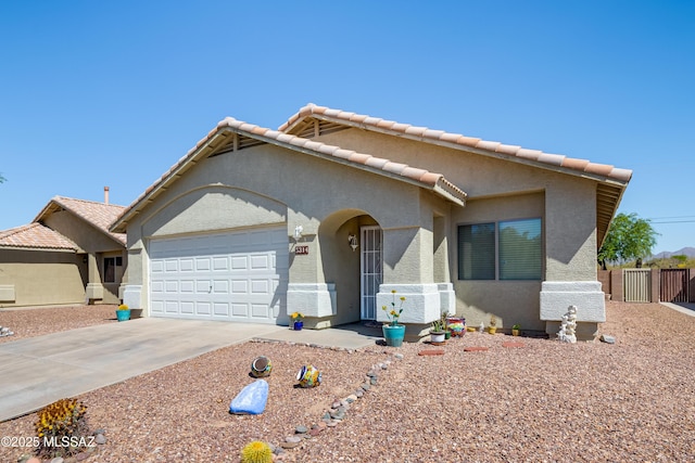 view of front of property with fence, a tiled roof, concrete driveway, an attached garage, and stucco siding