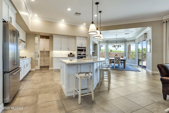 kitchen featuring visible vents, backsplash, light countertops, a tray ceiling, and appliances with stainless steel finishes