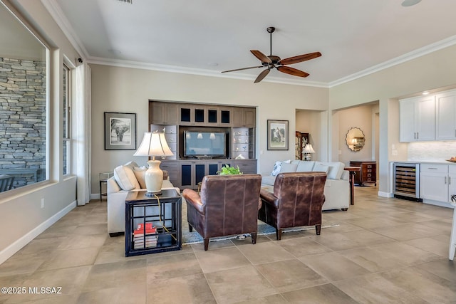 living area featuring bar area, beverage cooler, baseboards, ornamental molding, and ceiling fan