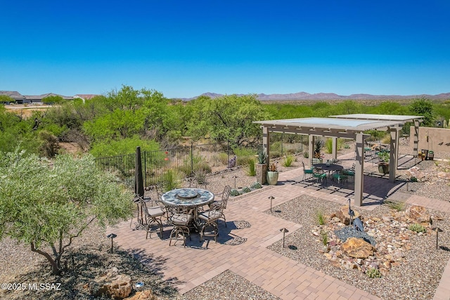view of patio featuring a mountain view, outdoor dining area, and fence