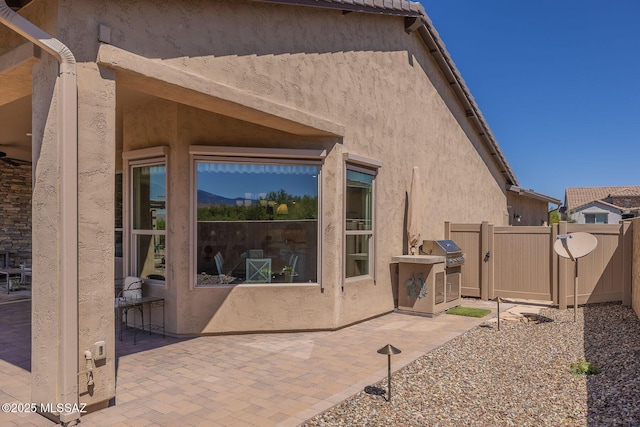 rear view of property with a patio, stucco siding, and fence
