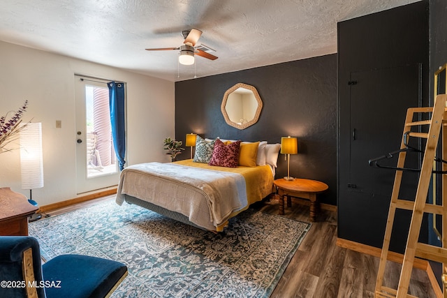bedroom featuring baseboards, wood finished floors, access to outside, and a textured ceiling