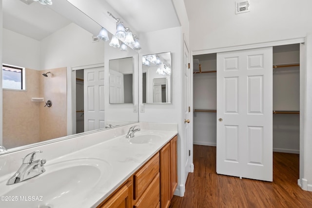 full bathroom featuring visible vents, a sink, a shower, and wood finished floors